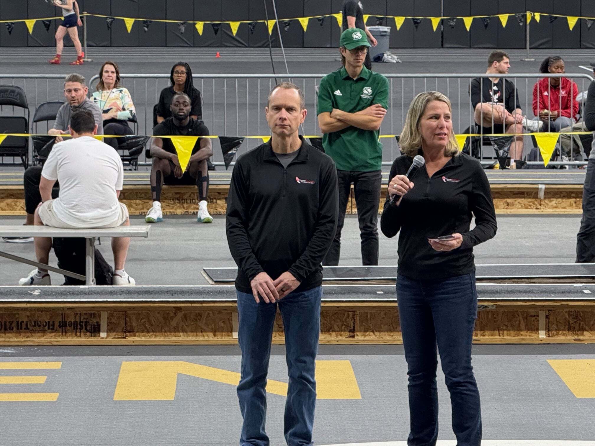 2025 Lauren McCluskey Memorial Track Meet at University of Idaho. Jill McCluskey and Matthew McCluskey speaking to audience about Lauren McCluskey Foundation.